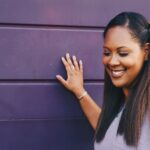 woman wearing purple shirt touching the wall