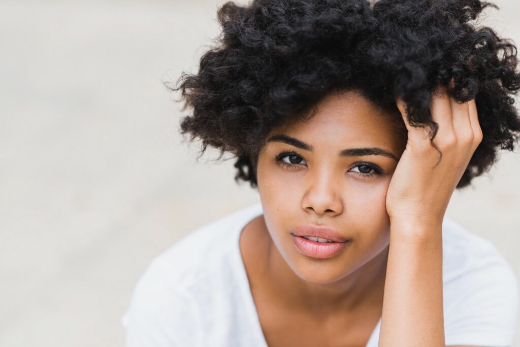 closeup portait beautiful young black woman with sad pensive reflective look against white wall background with copy space your text advertising content